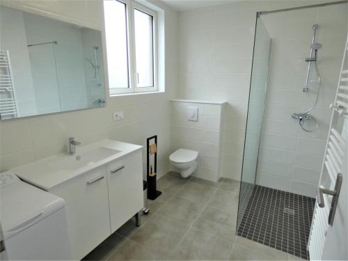 a white bathroom with a sink and a toilet at Le clémens in Herm