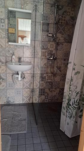 a bathroom with a sink and a shower with a mirror at Kapteni suvekodu in Laulasmaa