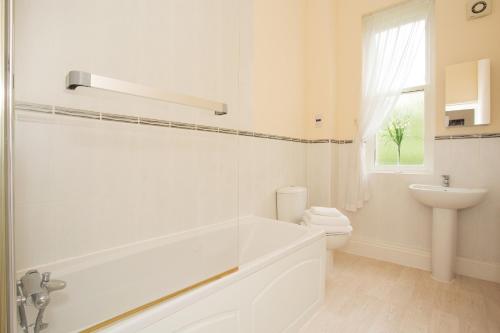 a white bathroom with a tub and a sink at Sherborne House, City Centre Victorian Apartments in Basingstoke
