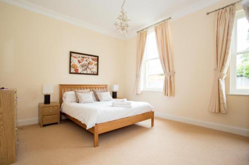 a bedroom with a bed and two windows at Sherborne House, City Centre Victorian Apartments in Basingstoke