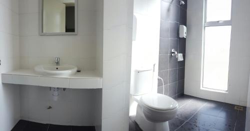 een witte badkamer met een wastafel en een toilet bij Feel Homestay in Cameron Highlands