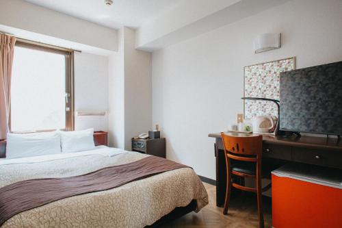 a hotel room with a bed and a desk and a window at Hamamatsu Station Hotel in Hamamatsu