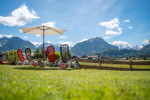 a group of chairs and an umbrella in the grass at Alpenhof Oberstdorf Hotel & SPA, Signature Collection by BW in Oberstdorf