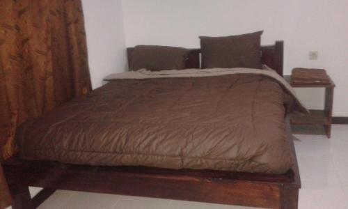 a bed in a bedroom with a wooden bed frame at Rock Pool Homestay in Huu