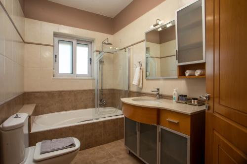 a bathroom with a tub and a toilet and a sink at Elysian View Estate in Faliraki