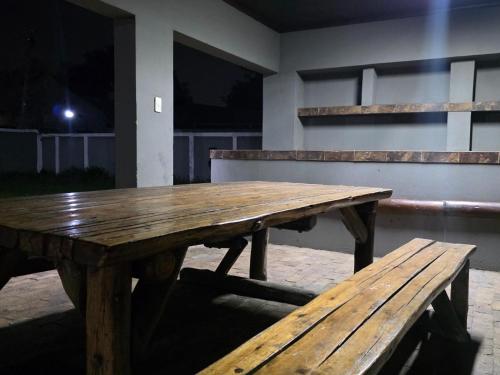 a wooden picnic table and bench in a room at Phola Lodge OR Tambo in Kempton Park