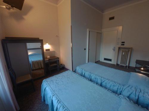 a hotel room with two beds and a mirror at Hotel Ada in Milan