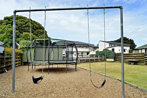 a swing set in a yard with a house at Takapuna Motor Lodge in Auckland