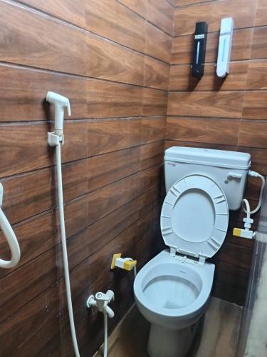 a bathroom with a toilet and a phone on the wall at The Little Braj Homestay in Mathura