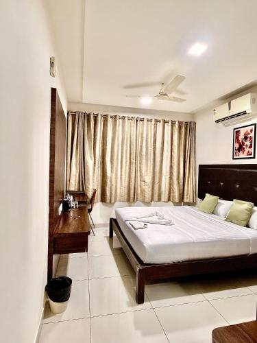 a bedroom with a bed and a desk and a window at The Staying Co in Bangalore