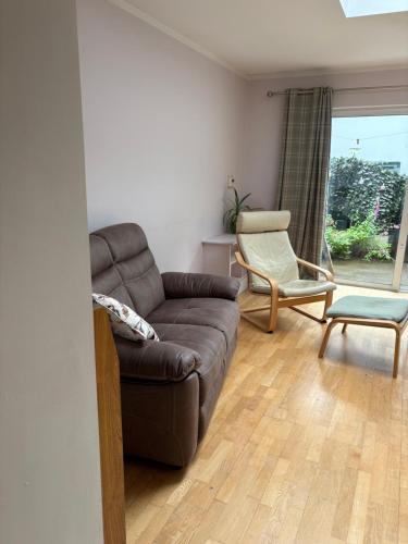 a living room with a brown couch and a chair at Town Centre House in Clonakilty