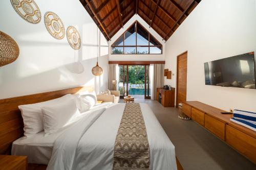 a bedroom with a white bed and a tv at Nayandra Uluwatu in Uluwatu