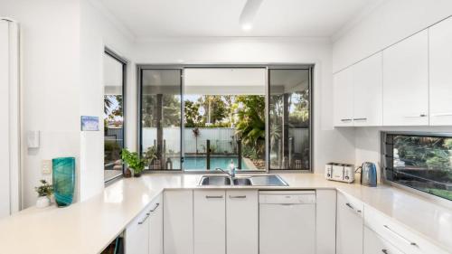 a white kitchen with a sink and a large window at Wave Whisperer Retreat in Woorim