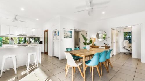 a kitchen and dining room with a wooden table and blue chairs at Wave Whisperer Retreat in Woorim