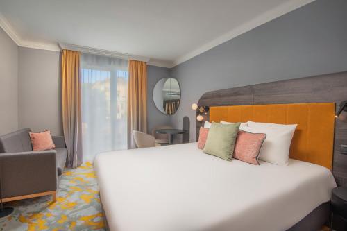 a hotel room with a large bed and a chair at Castrum Hotel Székesfehérvár in Székesfehérvár