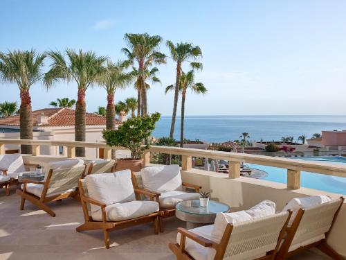 a patio with chairs and tables and a view of the ocean at Grecotel Marine Palace & Aqua Park in Panormos Rethymno