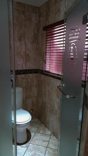 a bathroom with a toilet and a glass shower at Aark Guest Lodge in Vanderbijlpark