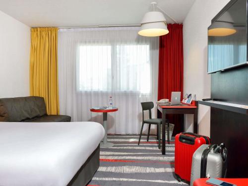 a hotel room with a bed and a chair and a table at ibis Styles Angoulême Nord in Champniers
