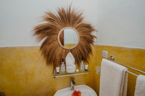 a bathroom with a mirror and a sink at Aquelia Rose Hotel in Jambiani