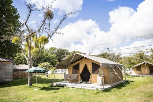 a tent in a field with trees in the background at Huttopia Calvados - Normandie in Moyaux