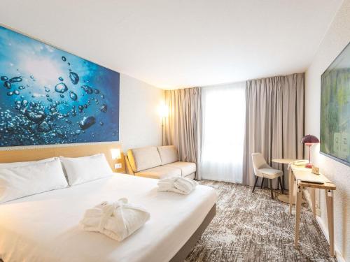 a hotel room with a bed and a desk at Novotel Grenoble Nord Voreppe in Voreppe