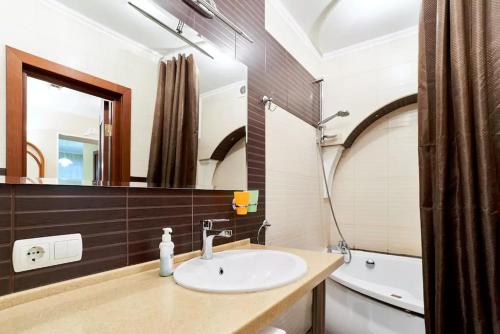 a bathroom with a sink and a mirror and a tub at Home Hotel Apartments on Kontraktova Ploshcha in Kyiv
