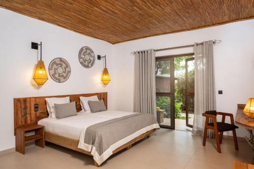 a bedroom with a bed and a table and a window at Royal Horizon Baobab in Somone
