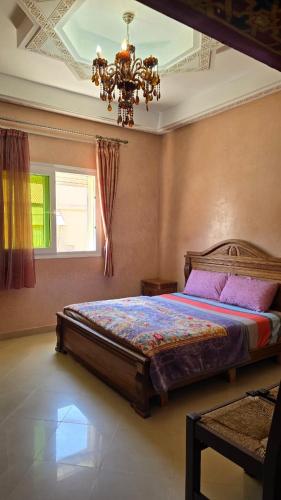 a bedroom with a bed and a chandelier at Appement in Agadir nʼ Aït Sa