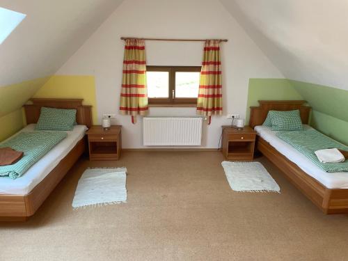 a attic room with two beds and a window at Landhaus Löscher in Seeboden