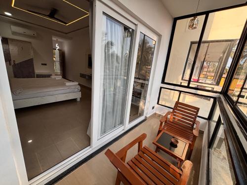 a room with a balcony with a chair and a bed at Shaan Coco Palms Beach Resort in Morjim