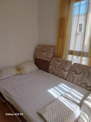 a small bedroom with a bed and a window at Апартамент Нина in Byala