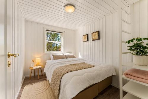 a white bedroom with a bed and a window at Lofoten Oceanfront - Privat Pier & Beach in Vestvågøya