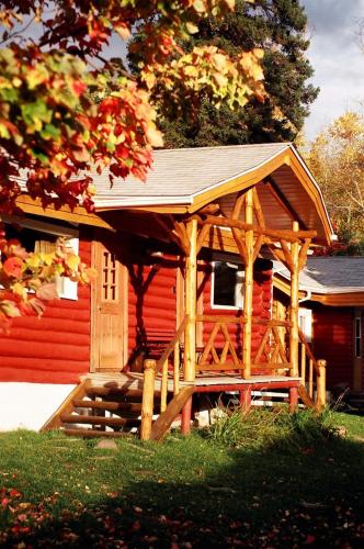 a wooden cabin with a porch in front of a house at Kan-à-Mouche Pourvoirie Auberge et Chalets in Saint-Michel-des-Saints