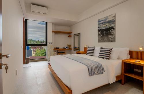 a bedroom with a large white bed and a large window at CASA MIA - Luxury Apartments Central Kuta in Kuta Lombok