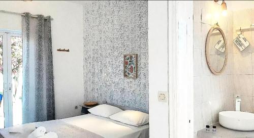 a bedroom with a bed and a sink and a mirror at Voula Accommodation in Agios Georgios