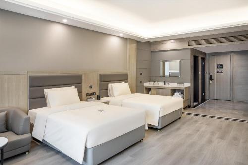 a hotel room with two beds and a chair at Atour Hotel Hotan Unity Plaza in Hoten