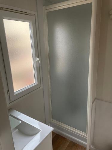 a bathroom with a sliding door and a mirror at Camping Le Bois De Pins in Salses-le-Chateau
