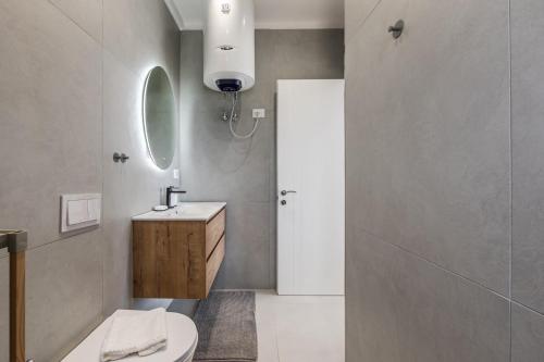 a bathroom with a sink and a toilet and a mirror at Boho Mar Drymadhes by PS in Dhërmi