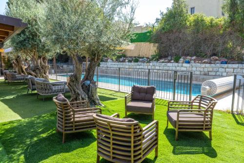 a group of chairs and a tree next to a pool at וילה ואמוס - Villa vamos - וילה מדהימה עם בריכה פרטית וג'קוזי in Rosh Pinna