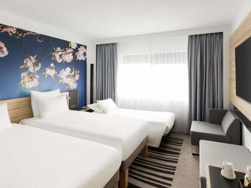 a hotel room with two beds and a couch at Novotel Amsterdam City in Amsterdam
