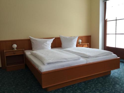 Schlafzimmer mit einem Bett mit weißer Bettwäsche und Kissen in der Unterkunft Waldgasthof & Hotel Alberthöhe in Lichtenstein