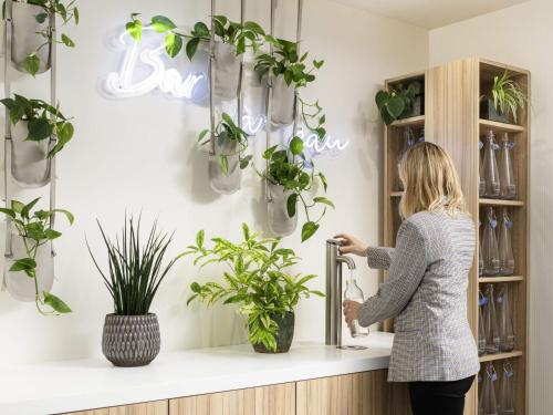 a woman standing in front of a shelf with plants at Novotel Lausanne Bussigny in Lausanne