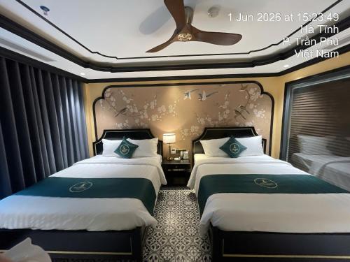 two beds in a hotel room with a ceiling fan at Hai Dang Hotel Ha Tinh in Hà Tĩnh
