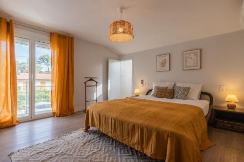 a bedroom with a bed and a large window at Villa NOVA in Capbreton