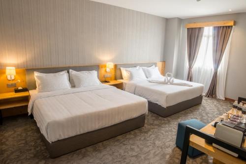 a hotel room with two beds and a desk at Redpine Hotel in Skudai