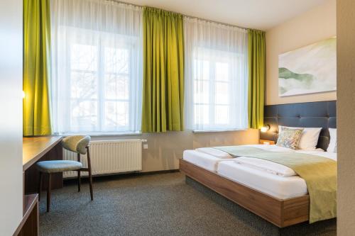 a hotel room with a bed and a desk and windows at JOESEPP´S HOTEL am Hallhof in Memmingen