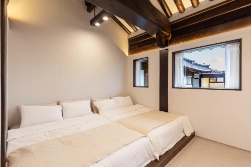 two beds in a room with a window at 한옥스테이 화랑루 in Gyeongju