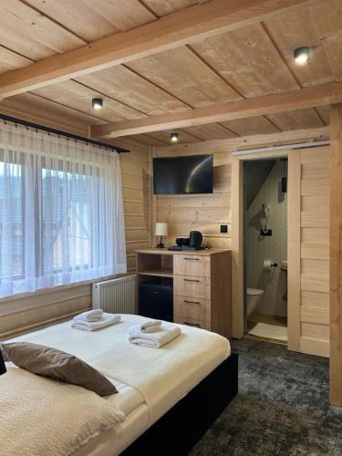 a bedroom with a large bed and a bathroom at Cichowiańska Chałupa przy stoku z widokiem na GÓRY I SKY WALK in Małe Ciche