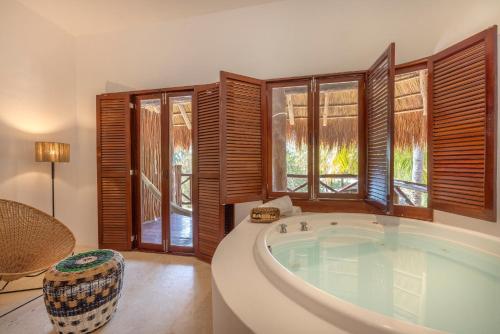 a bathroom with a large tub in a room with windows at Villas HM Paraiso del Mar in Holbox Island