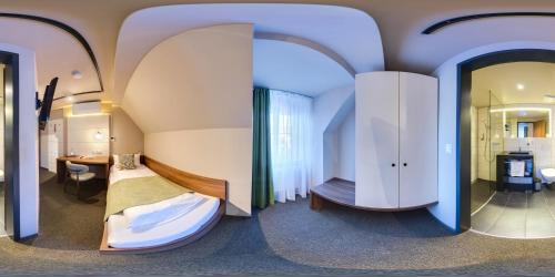 a room with a bed and a desk and a mirror at JOESEPP´S HOTEL am Hallhof in Memmingen